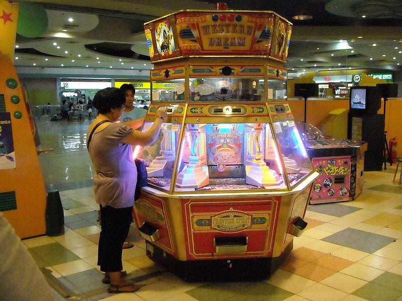 Coin Pusher Machine and How to Win on Them? 1 a lady inserting penny in a coin pusher machine